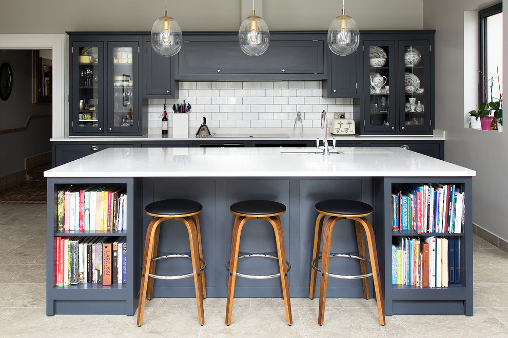 Inspiration for a mid-sized transitional kitchen remodel in London with blue cabinets, marble countertops, white backsplash, an island, an undermount sink, glass-front cabinets and subway tile backsplash