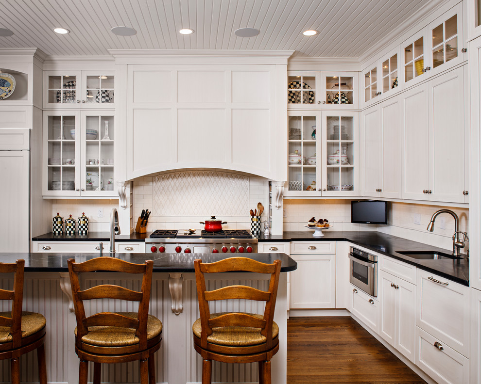 Example of a beach style l-shaped eat-in kitchen design in New York with an undermount sink, recessed-panel cabinets, white cabinets, soapstone countertops, white backsplash and stainless steel appliances