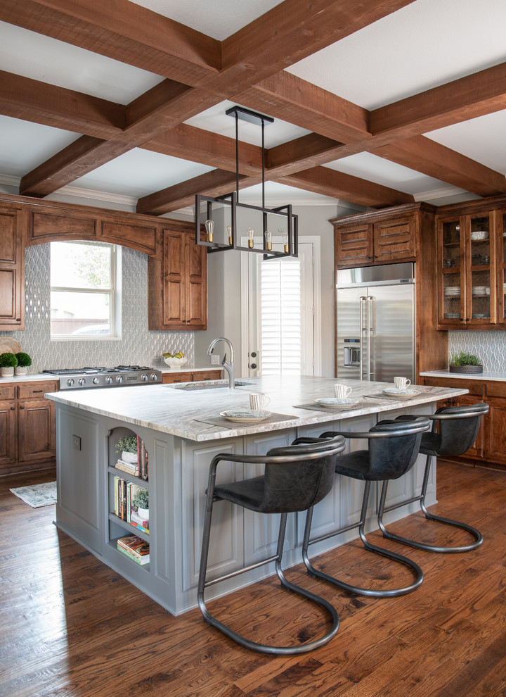 Inspiration for a large classic l-shaped kitchen in Dallas with a submerged sink, raised-panel cabinets, medium wood cabinets, engineered stone countertops, grey splashback, glass tiled splashback, stainless steel appliances, medium hardwood flooring, an island, brown floors and white worktops.