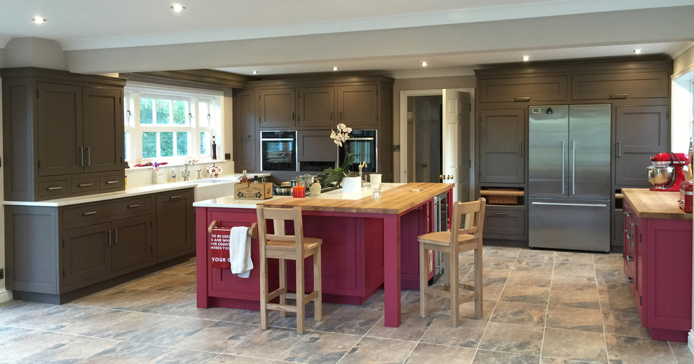 Photo of a rural l-shaped kitchen in Other with a belfast sink, recessed-panel cabinets, brown cabinets and an island.