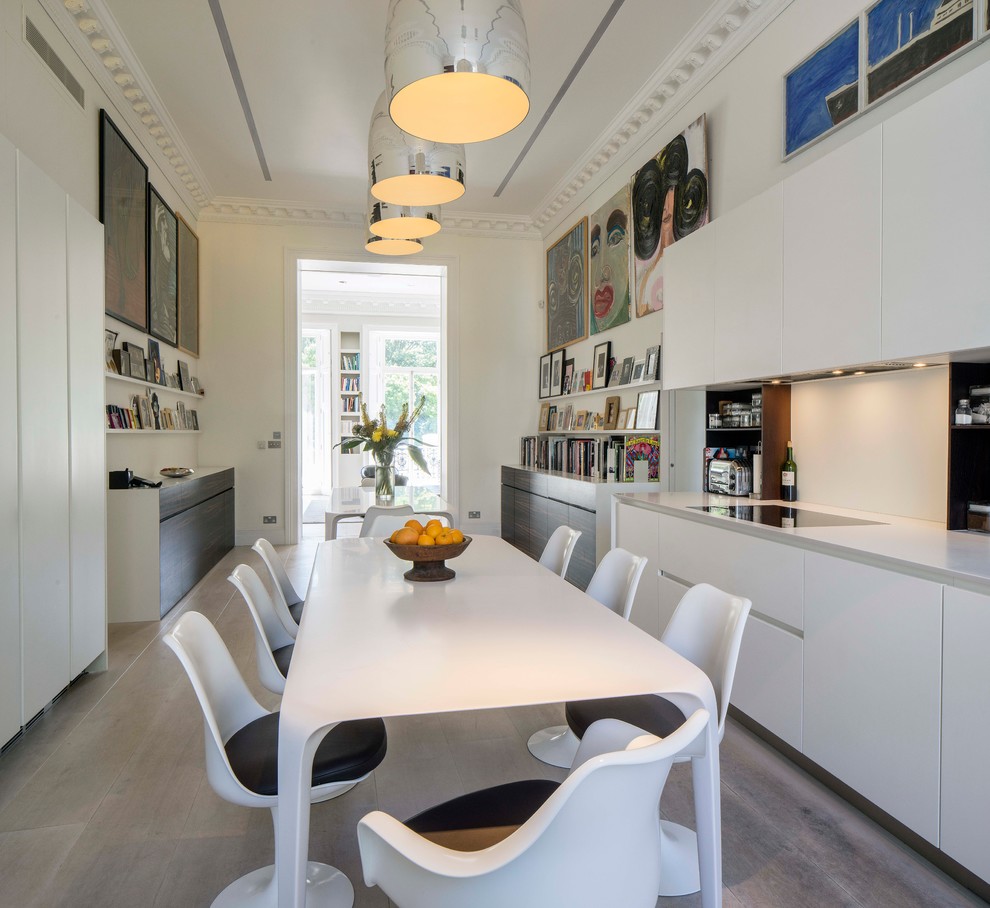 Zweizeilige Klassische Wohnküche ohne Insel mit flächenbündigen Schrankfronten, weißen Schränken, Mineralwerkstoff-Arbeitsplatte, Küchenrückwand in Weiß und hellem Holzboden in London
