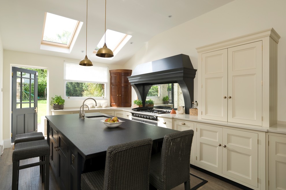 This is an example of a medium sized classic l-shaped enclosed kitchen in Essex with a submerged sink, flat-panel cabinets, quartz worktops, metallic splashback, mirror splashback, stainless steel appliances, dark hardwood flooring and an island.