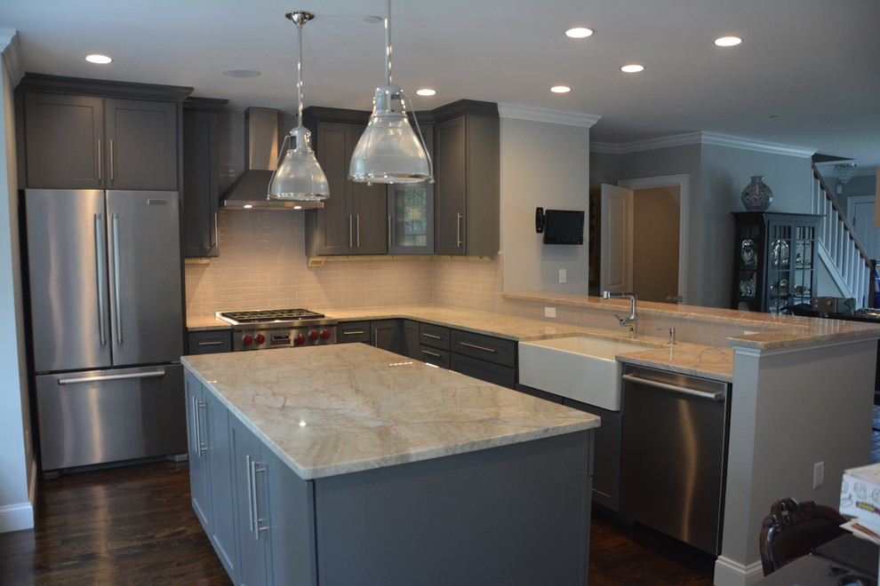 Example of a mid-sized transitional l-shaped dark wood floor eat-in kitchen design in Boston with a farmhouse sink, raised-panel cabinets, gray cabinets, quartzite countertops, gray backsplash, subway tile backsplash, stainless steel appliances and an island