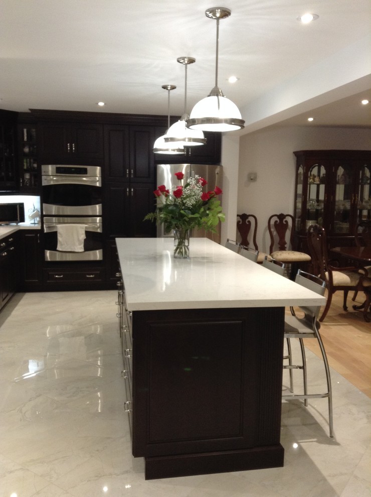 Example of a huge transitional u-shaped marble floor and gray floor enclosed kitchen design in Toronto with raised-panel cabinets, dark wood cabinets, solid surface countertops, stainless steel appliances and an island