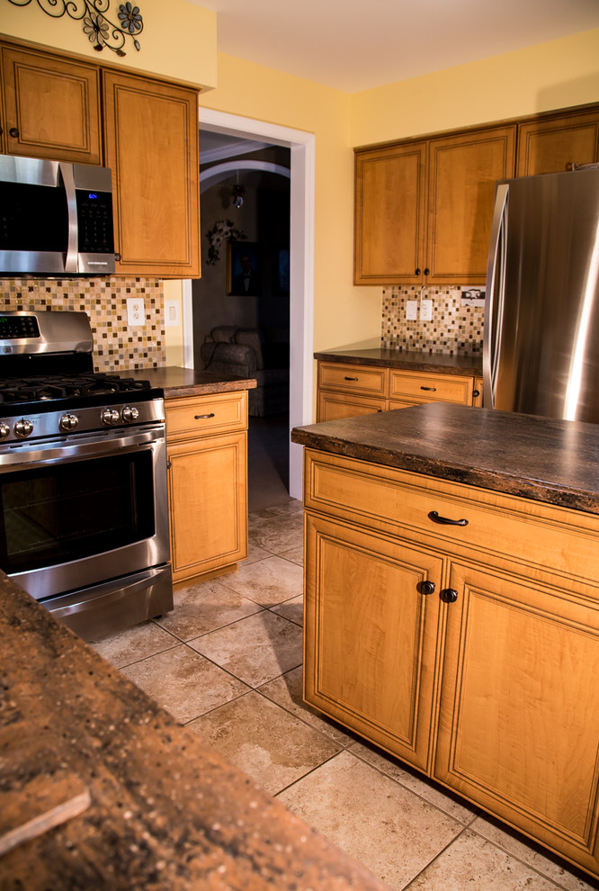 Klassisk inredning av ett mellanstort u-kök, med en dubbel diskho, luckor med infälld panel, skåp i mellenmörkt trä, laminatbänkskiva, flerfärgad stänkskydd, rostfria vitvaror, stänkskydd i mosaik, klinkergolv i keramik och en köksö