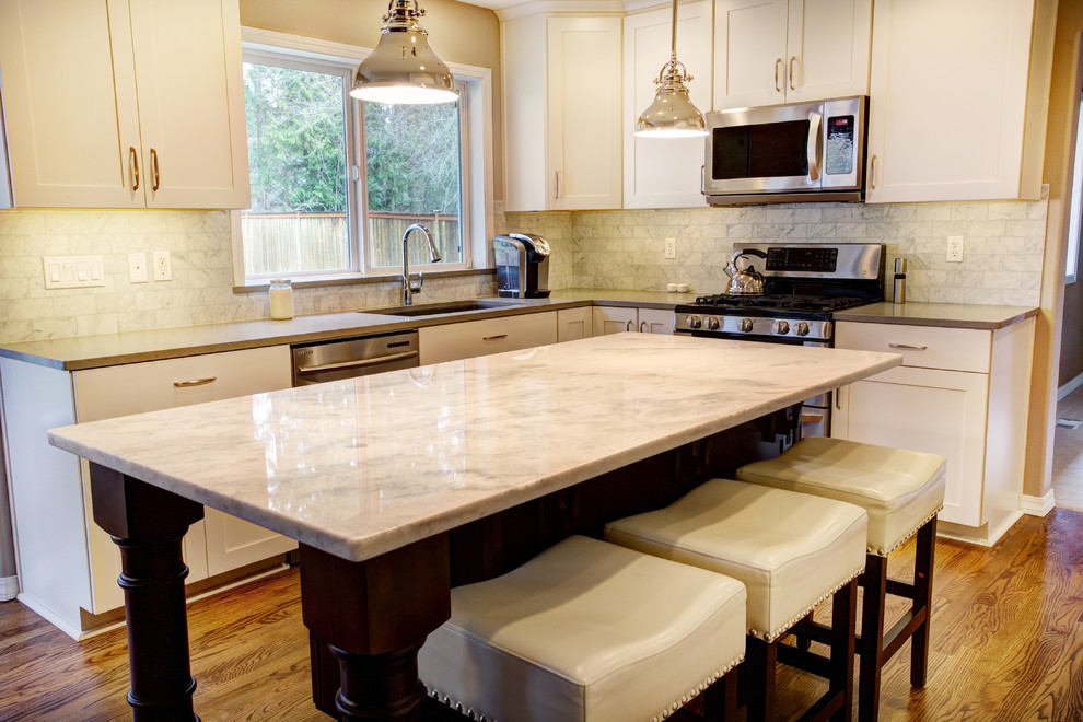 Foto på ett mellanstort vintage kök, med en undermonterad diskho, luckor med infälld panel, vita skåp, bänkskiva i kvarts, vitt stänkskydd, stänkskydd i stenkakel, rostfria vitvaror, mellanmörkt trägolv och en köksö