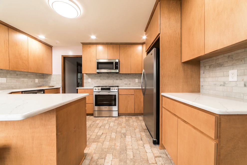 Inspiration for a mid-sized transitional l-shaped ceramic tile and multicolored floor eat-in kitchen remodel in Chicago with an undermount sink, flat-panel cabinets, light wood cabinets, quartz countertops, multicolored backsplash, ceramic backsplash, stainless steel appliances, a peninsula and multicolored countertops