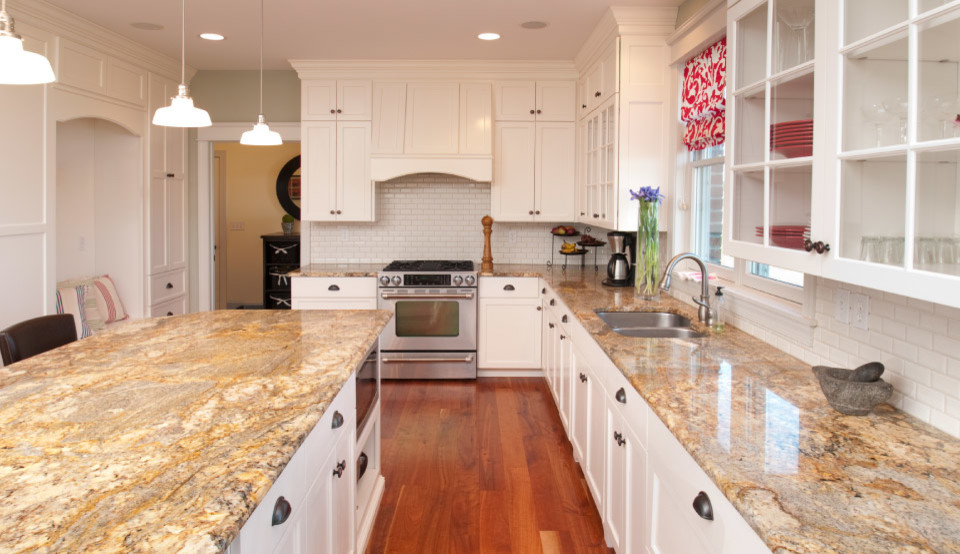 Klassisk inredning av ett avskilt, mellanstort l-kök, med en undermonterad diskho, luckor med infälld panel, vita skåp, granitbänkskiva, vitt stänkskydd, stänkskydd i keramik, rostfria vitvaror, mellanmörkt trägolv och en köksö