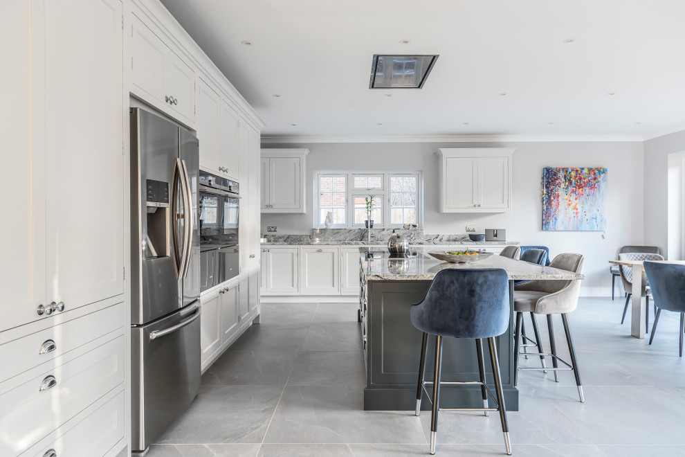 Large classic l-shaped kitchen/diner in Berkshire with shaker cabinets, grey cabinets, marble worktops, grey splashback, marble splashback, integrated appliances, an island, grey worktops and grey floors.