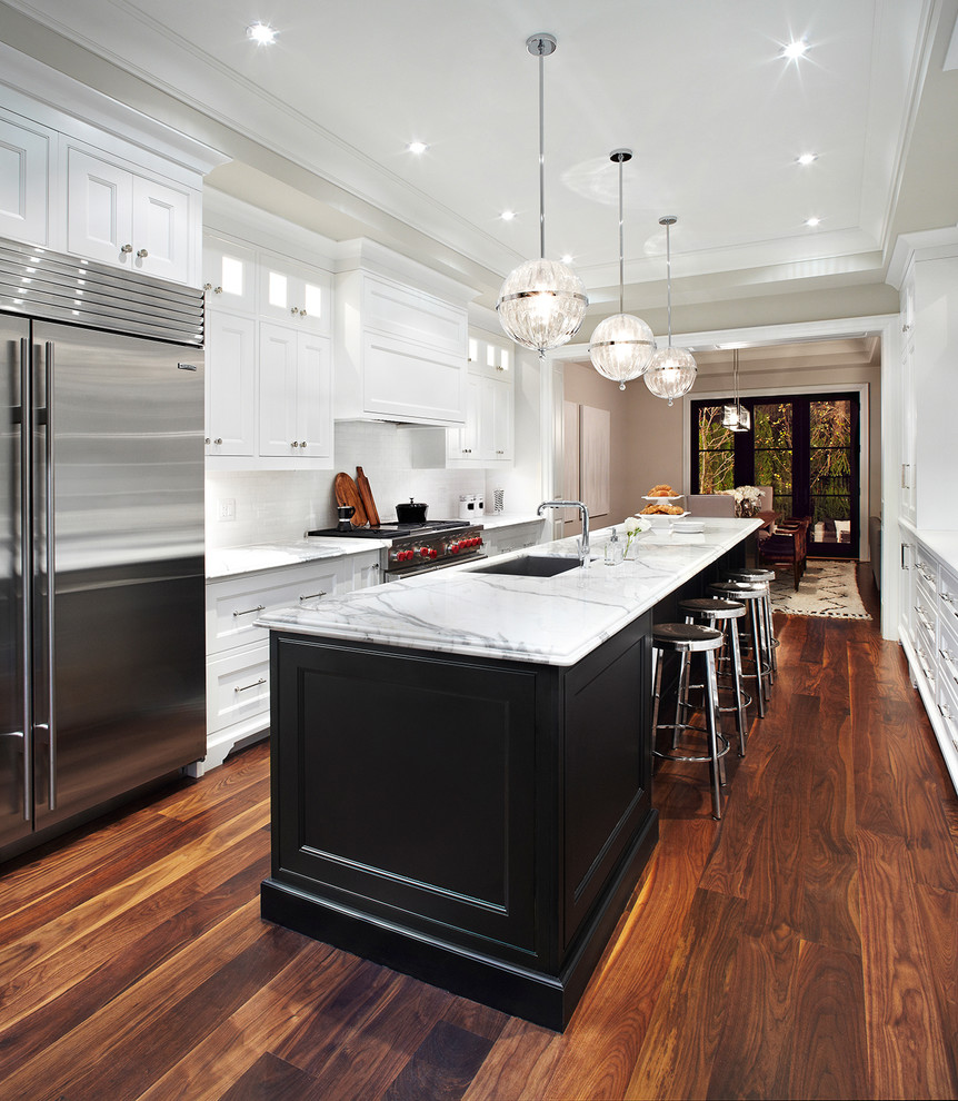 This is an example of a traditional galley kitchen/diner in Dallas with a submerged sink, recessed-panel cabinets, white splashback and stainless steel appliances.