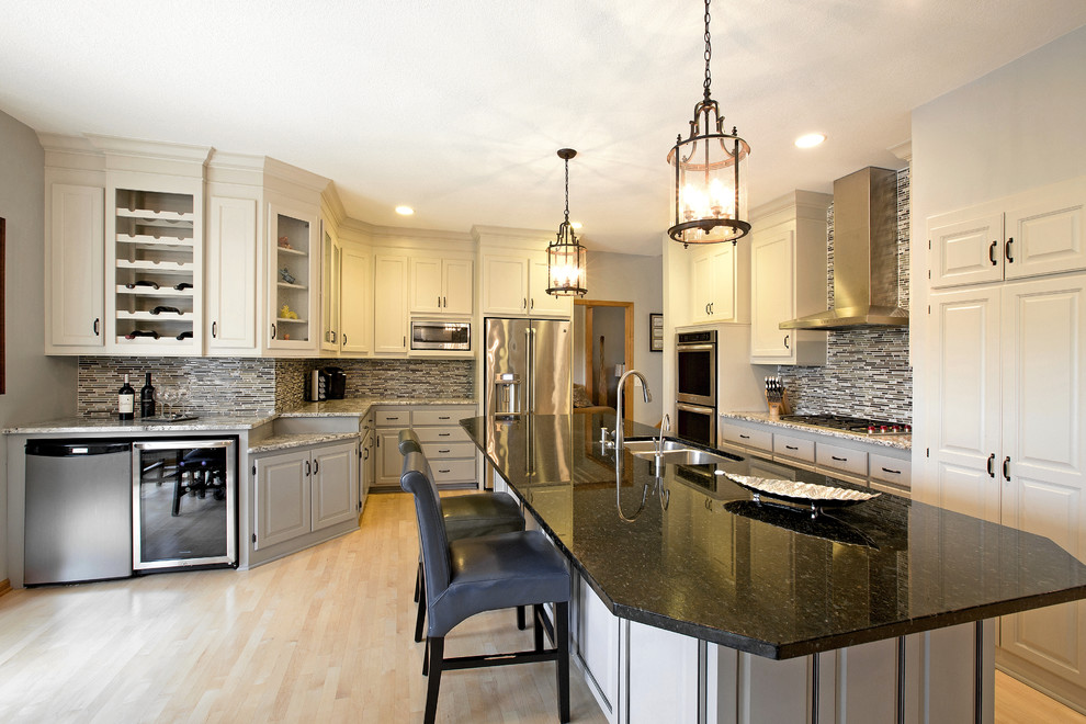 Inspiration for a mid-sized transitional u-shaped light wood floor eat-in kitchen remodel in Minneapolis with a drop-in sink, raised-panel cabinets, beige cabinets, laminate countertops, gray backsplash, glass tile backsplash, stainless steel appliances and an island