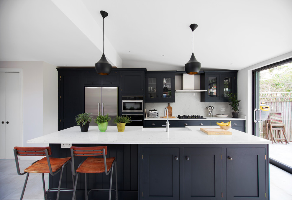 Design ideas for a traditional kitchen in London with stainless steel appliances, an island, white worktops, grey floors, grey splashback, glass-front cabinets and black cabinets.