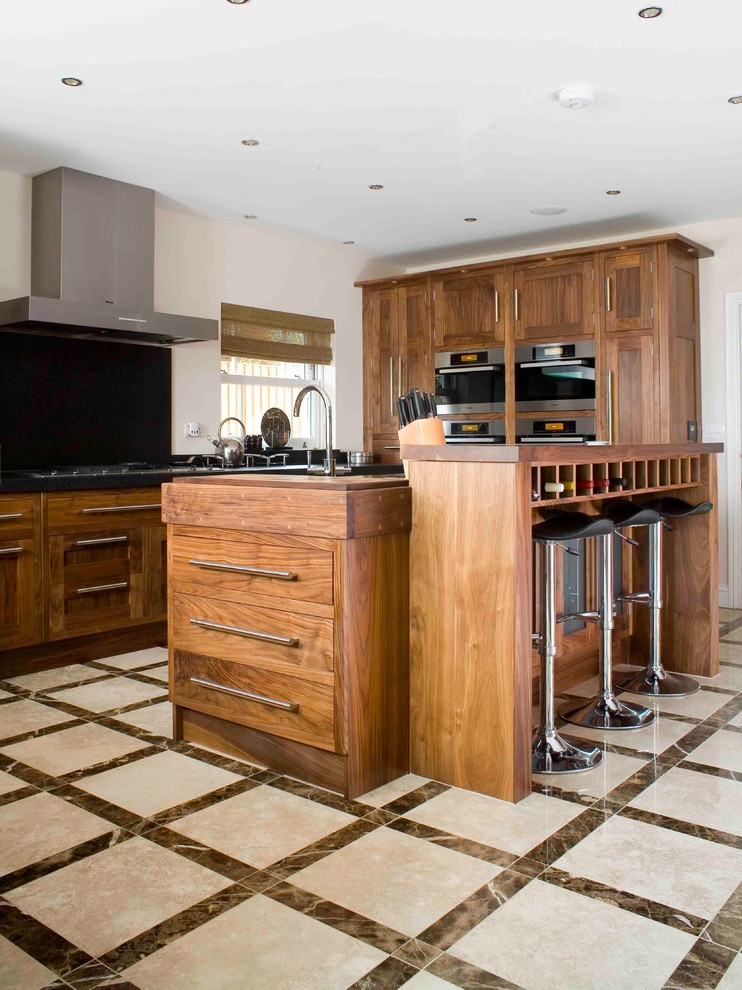 Klassische Küche mit Schrankfronten im Shaker-Stil, hellbraunen Holzschränken und Küchenrückwand in Schwarz in Essex