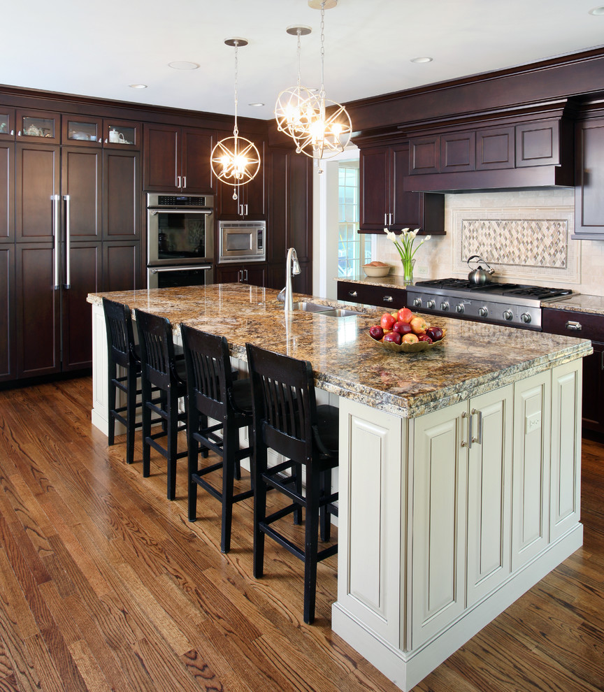 Open concept kitchen - large traditional l-shaped medium tone wood floor open concept kitchen idea in Chicago with a double-bowl sink, recessed-panel cabinets, dark wood cabinets, granite countertops, beige backsplash, stainless steel appliances and an island