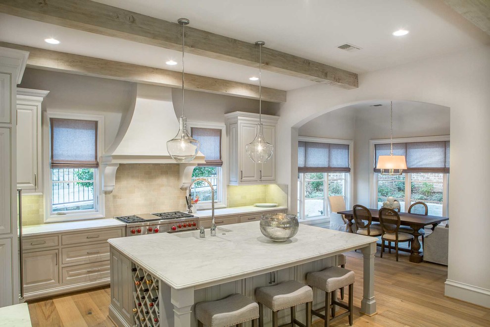 Example of a large transitional single-wall light wood floor open concept kitchen design in Dallas with recessed-panel cabinets, white cabinets, marble countertops, beige backsplash, stone tile backsplash, stainless steel appliances and an island