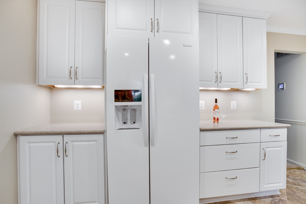 Kitchen - mid-sized transitional u-shaped kitchen idea in DC Metro with an undermount sink, raised-panel cabinets, white cabinets, glass countertops, white backsplash, white appliances and an island