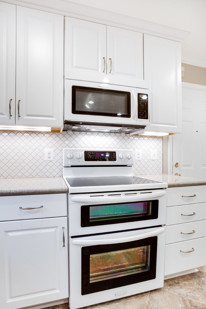 Foto di una cucina chic di medie dimensioni con lavello sottopiano, ante con bugna sagomata, ante bianche, top in vetro, paraspruzzi bianco e elettrodomestici bianchi