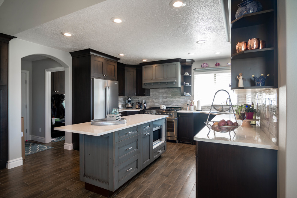 This is an example of a large classic u-shaped kitchen/diner in Salt Lake City with a built-in sink, recessed-panel cabinets, dark wood cabinets, engineered stone countertops, grey splashback, stone tiled splashback, stainless steel appliances, vinyl flooring, an island and brown floors.