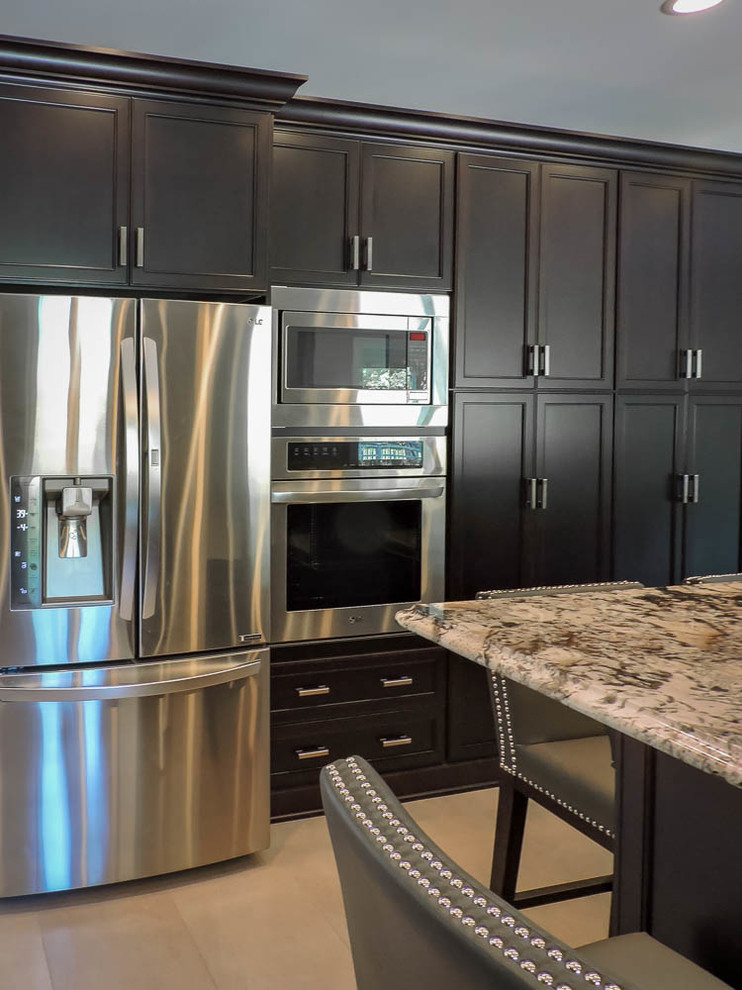 Example of a large transitional u-shaped porcelain tile and beige floor eat-in kitchen design in Bridgeport with an undermount sink, raised-panel cabinets, dark wood cabinets, granite countertops, green backsplash, glass tile backsplash, stainless steel appliances, an island and brown countertops
