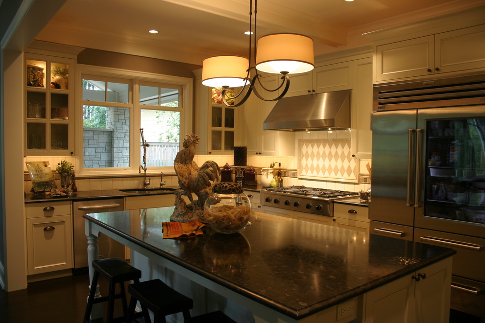 Example of a large transitional u-shaped dark wood floor and brown floor kitchen design in Austin with an undermount sink, recessed-panel cabinets, white cabinets, granite countertops, white backsplash, ceramic backsplash, stainless steel appliances and an island