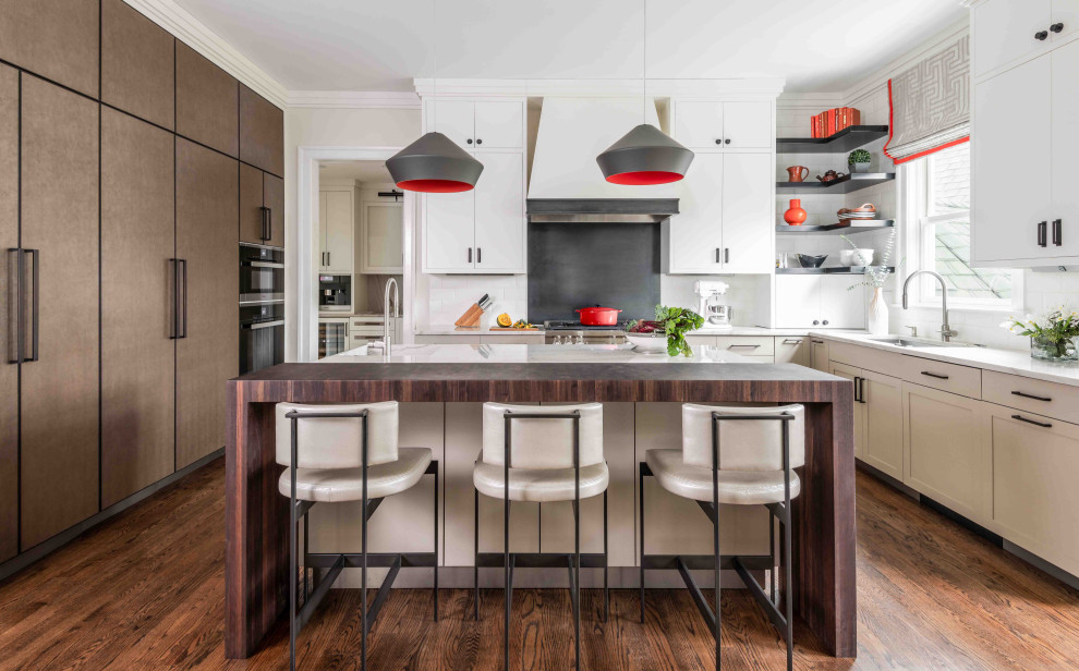 Klassisk inredning av ett brun brunt u-kök, med en undermonterad diskho, skåp i shakerstil, vita skåp, träbänkskiva, rött stänkskydd, integrerade vitvaror, mellanmörkt trägolv, en köksö och brunt golv