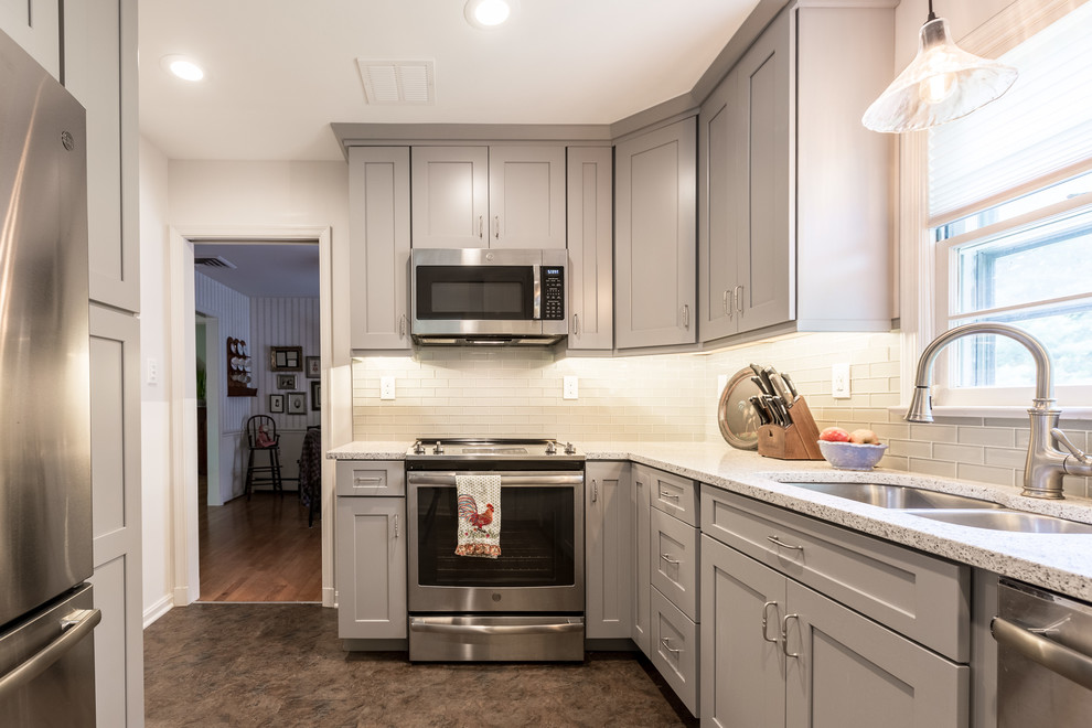 Example of a small transitional galley brown floor enclosed kitchen design in DC Metro with a double-bowl sink, shaker cabinets, gray cabinets, glass tile backsplash, stainless steel appliances, no island and gray countertops