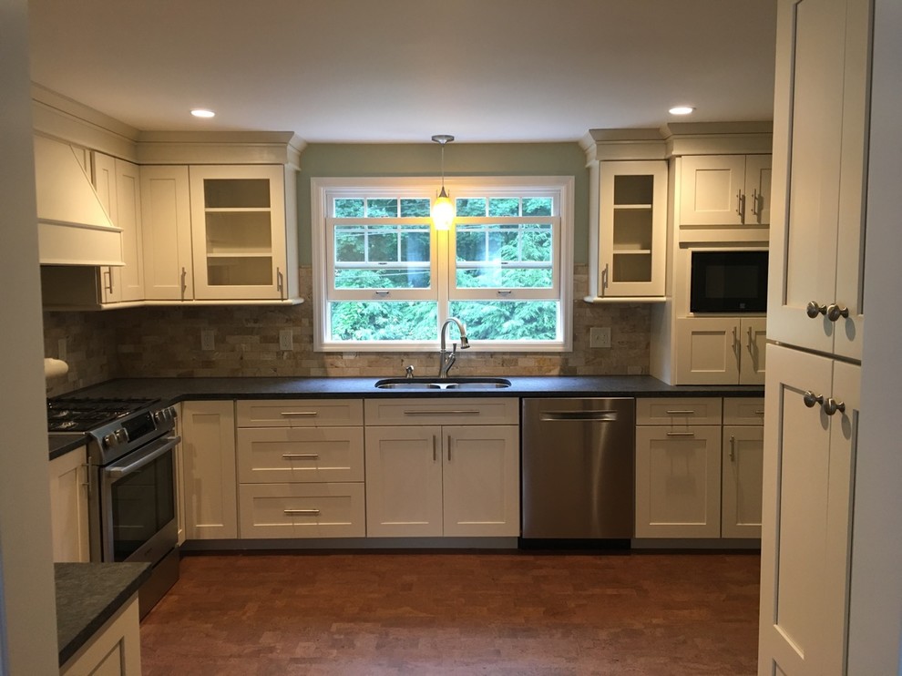 Photo of a medium sized traditional l-shaped kitchen/diner in New York with a submerged sink, shaker cabinets, white cabinets, granite worktops, beige splashback, stone tiled splashback, stainless steel appliances, cork flooring, no island and brown floors.