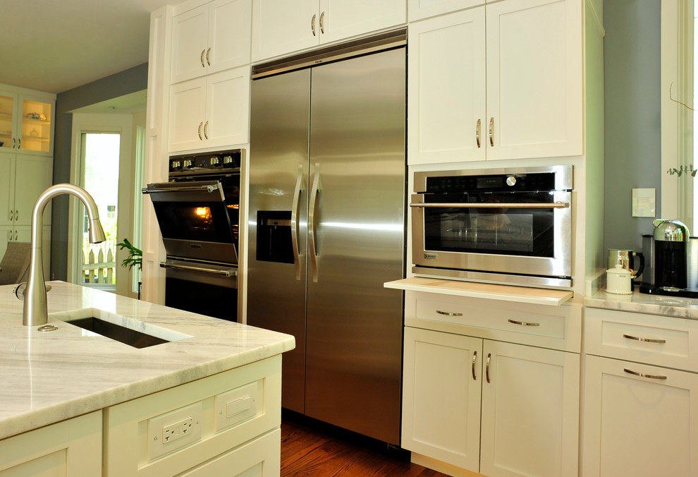 Exempel på ett stort klassiskt u-kök, med en undermonterad diskho, skåp i shakerstil, vita skåp, granitbänkskiva, rostfria vitvaror, mellanmörkt trägolv och en köksö