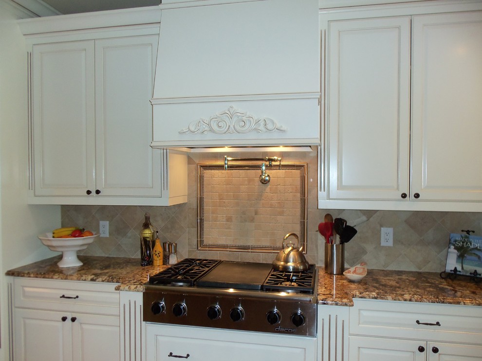 Foto de cocinas en U clásico grande abierto con armarios con paneles con relieve, encimera de granito y una isla