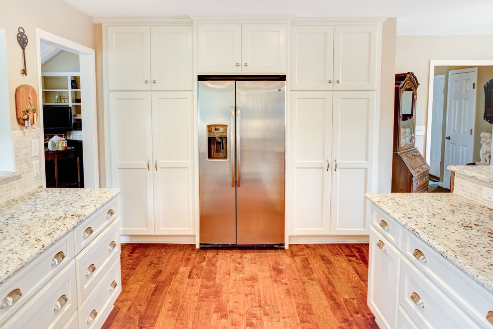 Foto på ett stort lantligt u-kök, med en undermonterad diskho, luckor med infälld panel, granitbänkskiva, rostfria vitvaror, mellanmörkt trägolv och en halv köksö