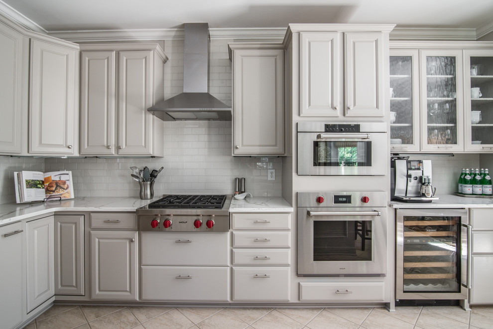 Inspiration for a large transitional l-shaped porcelain tile eat-in kitchen remodel in Charlotte with a double-bowl sink, raised-panel cabinets, gray cabinets, quartz countertops, gray backsplash, subway tile backsplash, stainless steel appliances and a peninsula