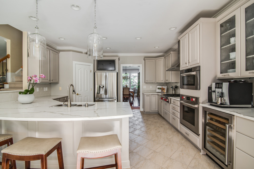 Large traditional l-shaped kitchen/diner in Charlotte with a double-bowl sink, raised-panel cabinets, grey cabinets, engineered stone countertops, grey splashback, metro tiled splashback, stainless steel appliances, porcelain flooring and a breakfast bar.