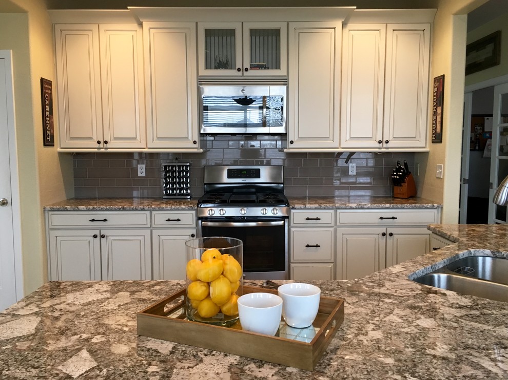 Immagine di una cucina classica di medie dimensioni con lavello sottopiano, ante con bugna sagomata, ante beige, top in granito, paraspruzzi beige, paraspruzzi con piastrelle diamantate e elettrodomestici in acciaio inossidabile