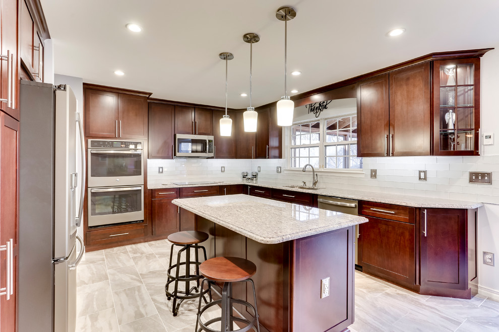 Photo of a medium sized classic u-shaped kitchen in DC Metro with a submerged sink, shaker cabinets, granite worktops, white splashback, stainless steel appliances and an island.