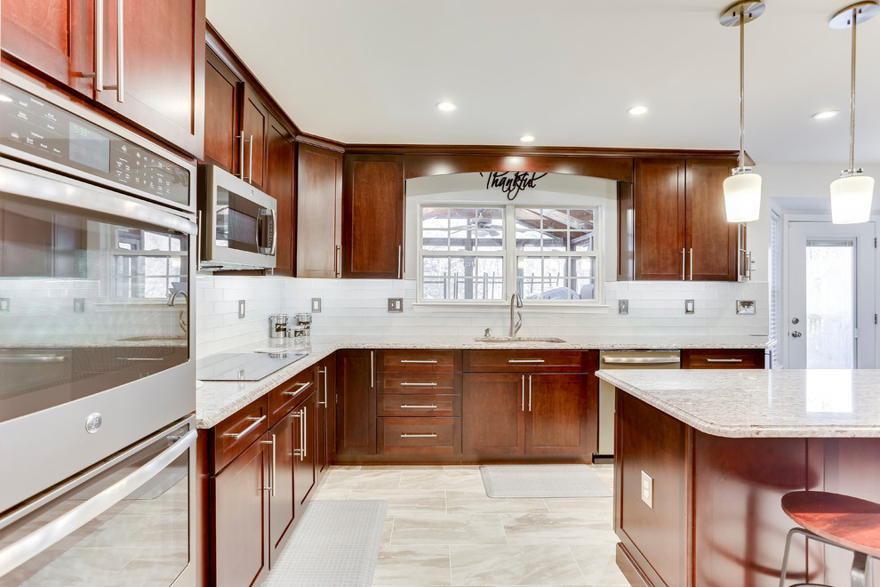 This is an example of a medium sized traditional u-shaped kitchen in DC Metro with a submerged sink, shaker cabinets, granite worktops, white splashback, stainless steel appliances and an island.