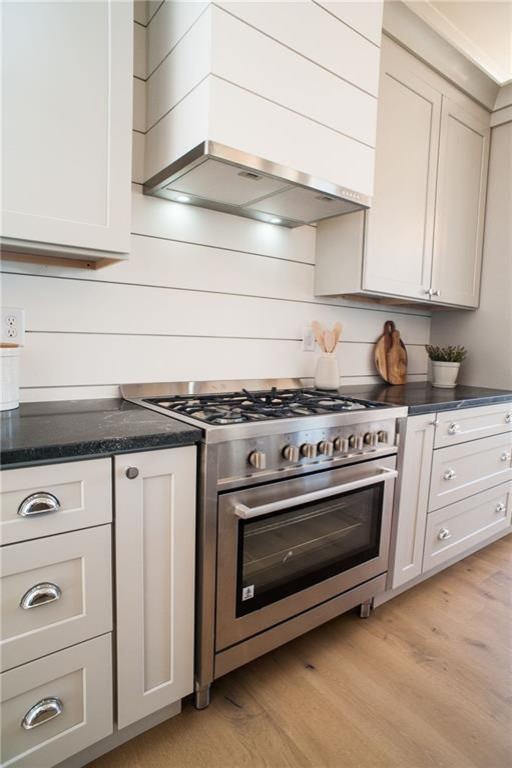 Medium sized traditional l-shaped open plan kitchen in Miami with a submerged sink, shaker cabinets, white cabinets, onyx worktops, white splashback, wood splashback, stainless steel appliances, light hardwood flooring, an island, beige floors and black worktops.