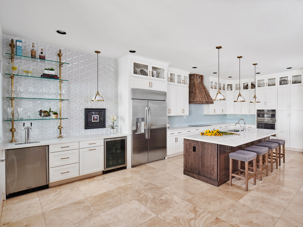 Photo of an expansive traditional l-shaped open plan kitchen in Phoenix with a submerged sink, recessed-panel cabinets, white cabinets, engineered stone countertops, blue splashback, porcelain splashback, stainless steel appliances, travertine flooring, an island, beige floors and white worktops.