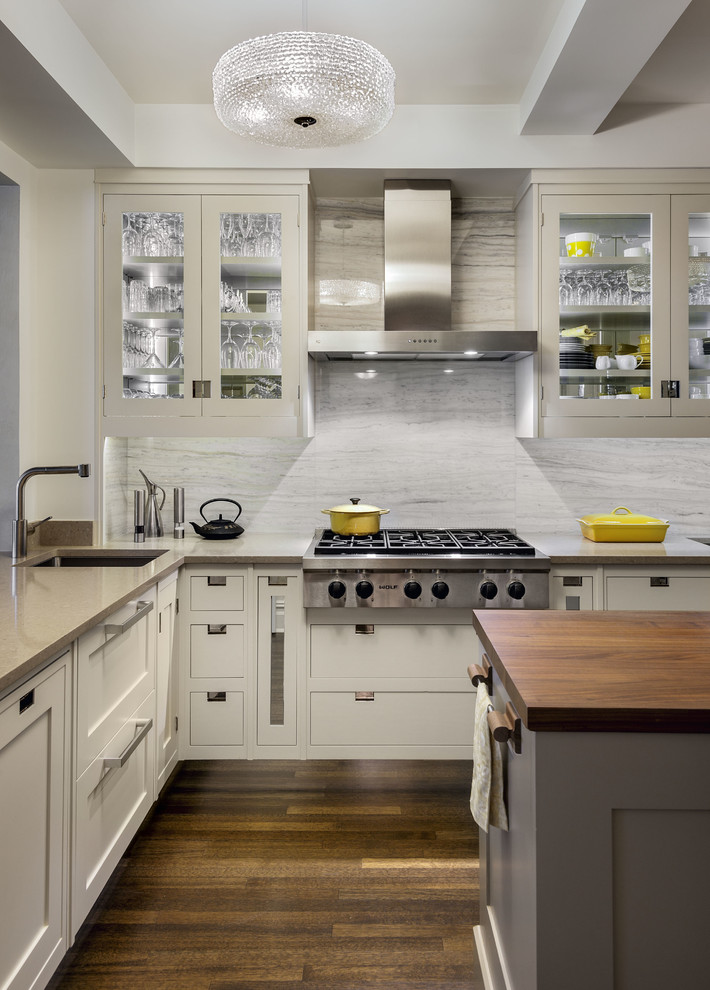 Transitional l-shaped dark wood floor kitchen photo in New York with an undermount sink, shaker cabinets, white cabinets, white backsplash, stone slab backsplash, stainless steel appliances and an island