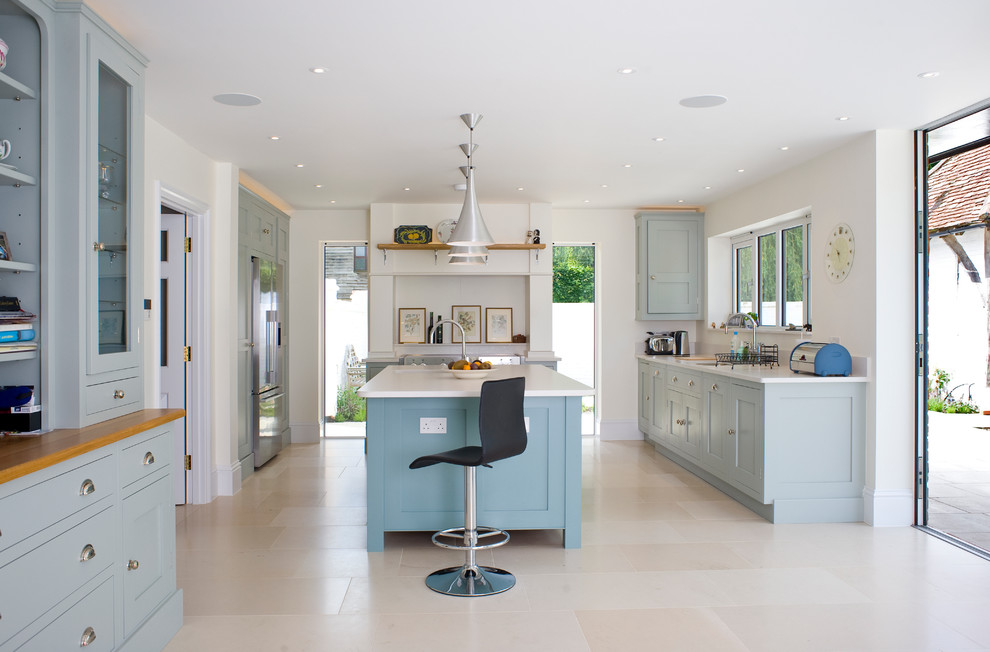 Classic kitchen in London with shaker cabinets, blue cabinets, stainless steel appliances and an island.