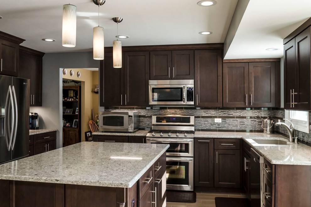Mid-sized transitional l-shaped porcelain tile open concept kitchen photo in Chicago with an undermount sink, raised-panel cabinets, dark wood cabinets, quartz countertops, stainless steel appliances, gray backsplash and matchstick tile backsplash