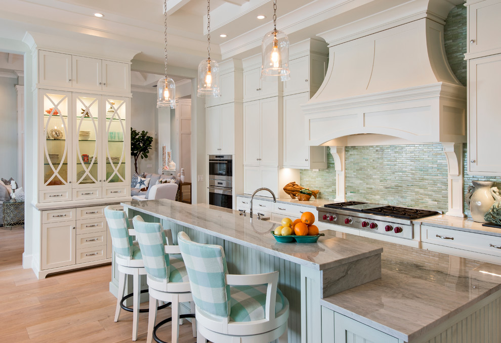 Photo of a traditional l-shaped kitchen in Miami with shaker cabinets, white cabinets, green splashback, matchstick tiled splashback, stainless steel appliances, light hardwood flooring and an island.