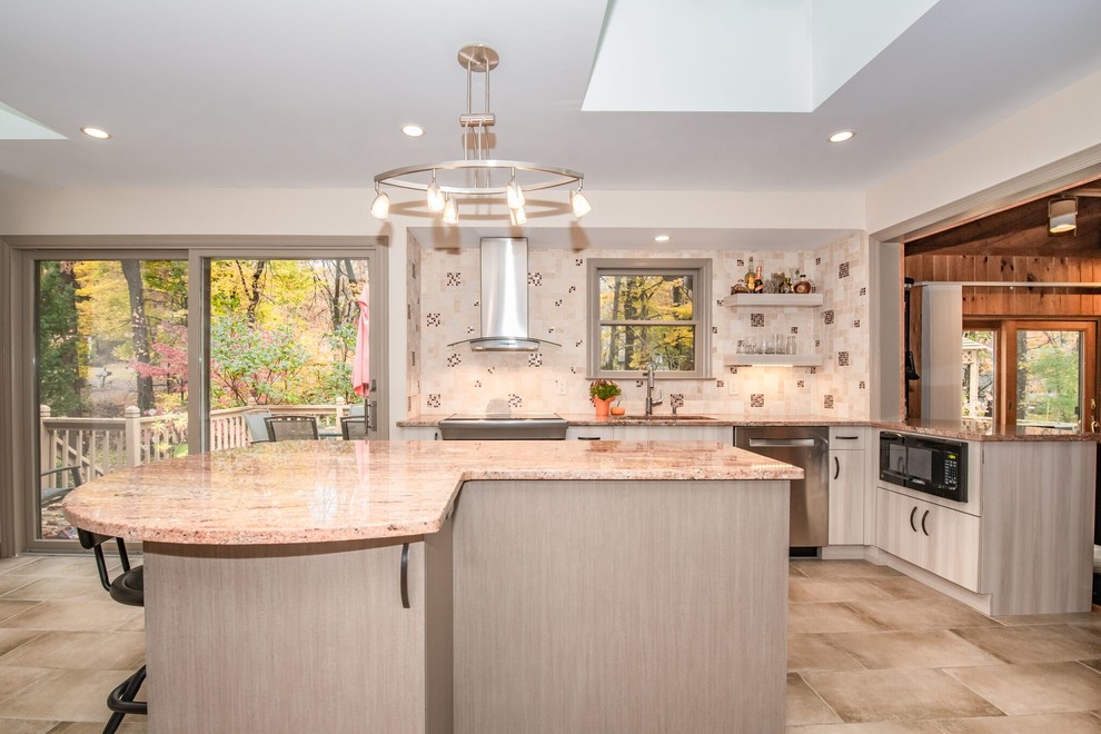 Inspiration for a large transitional l-shaped ceramic tile and beige floor eat-in kitchen remodel in New York with a drop-in sink, flat-panel cabinets, beige cabinets, granite countertops, beige backsplash, stone tile backsplash, stainless steel appliances, an island and beige countertops