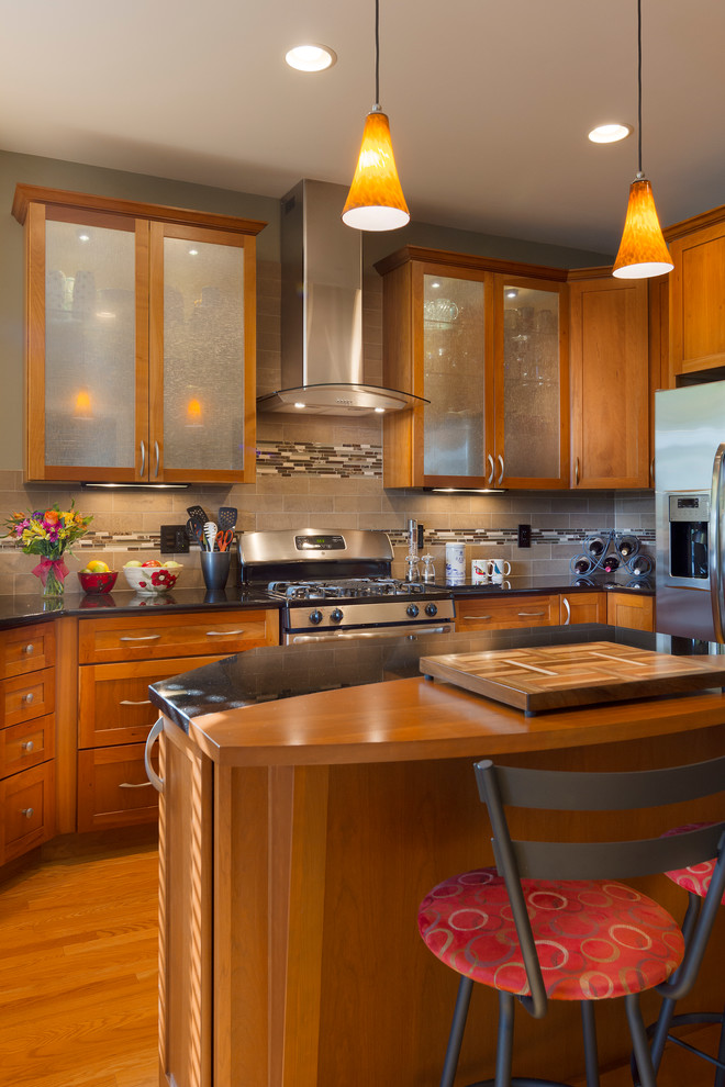 Klassische Küchenbar mit Glasfronten, hellbraunen Holzschränken, bunter Rückwand, Küchengeräten aus Edelstahl, braunem Holzboden und Kücheninsel in Sonstige