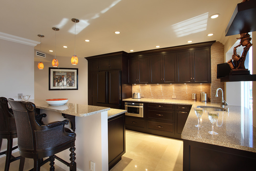 Example of a large transitional l-shaped ceramic tile and beige floor eat-in kitchen design in Miami with stainless steel appliances, dark wood cabinets, a drop-in sink, recessed-panel cabinets, terrazzo countertops, beige backsplash, glass tile backsplash, an island and multicolored countertops