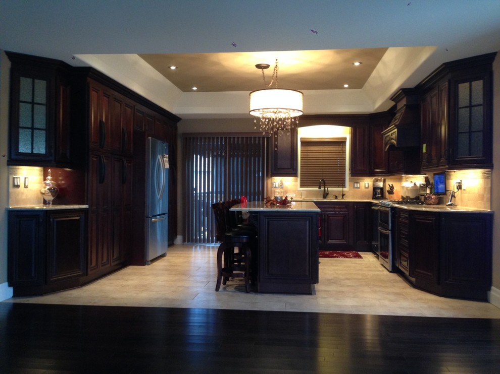 Klassische Küche in U-Form mit Glasfronten, hellbraunen Holzschränken, Küchenrückwand in Beige, Küchengeräten aus Edelstahl, gebeiztem Holzboden und Kücheninsel in Toronto