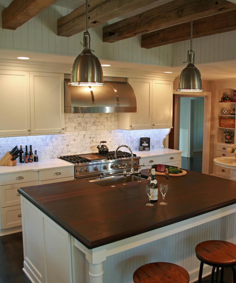 Foto di un cucina con isola centrale classico con ante con riquadro incassato, ante bianche, elettrodomestici da incasso e parquet scuro