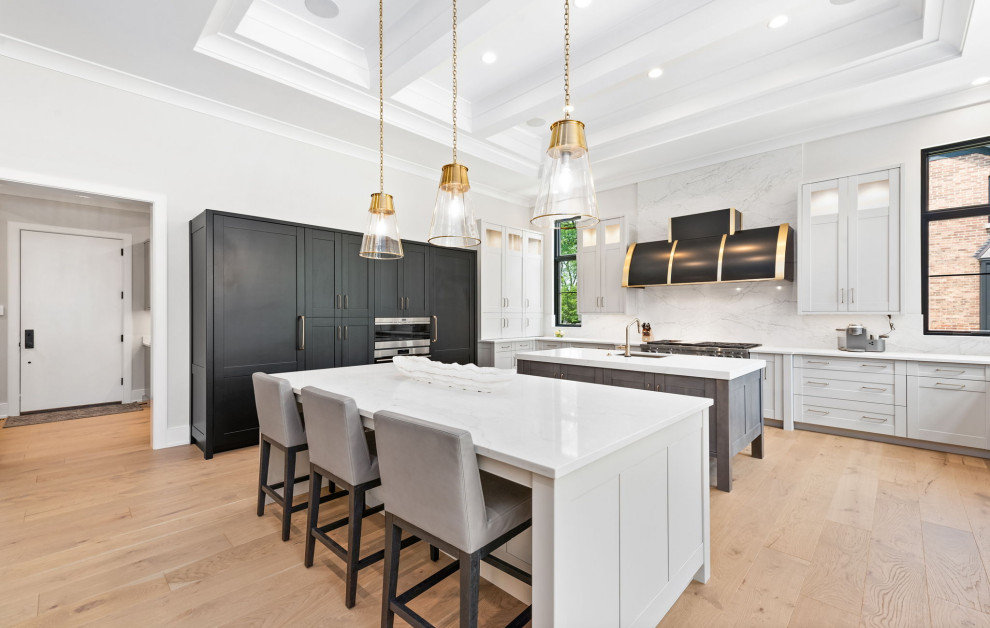 Photo of an expansive traditional u-shaped kitchen in Chicago with a submerged sink, shaker cabinets, grey cabinets, engineered stone countertops, white splashback, engineered quartz splashback, stainless steel appliances, light hardwood flooring, multiple islands, white worktops, beige floors and a drop ceiling.