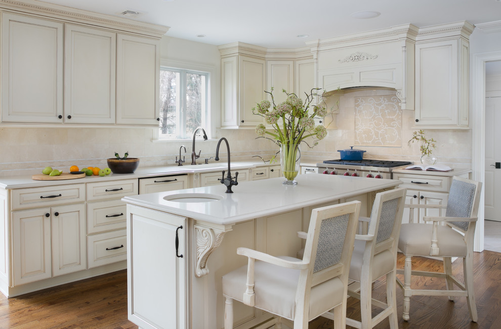 Inspiration for a large transitional l-shaped medium tone wood floor eat-in kitchen remodel in Newark with a single-bowl sink, beige cabinets, quartzite countertops, beige backsplash, stone tile backsplash, paneled appliances, an island and raised-panel cabinets
