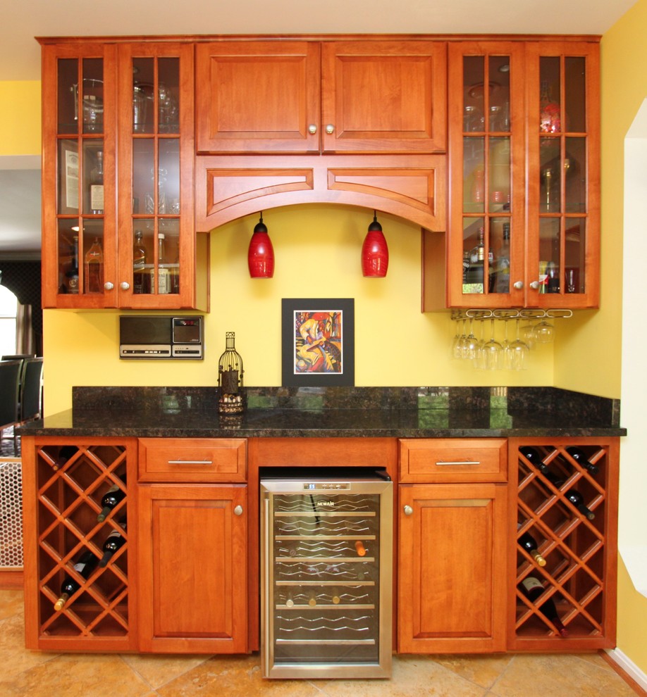 Photo of a traditional home bar in Baltimore with raised-panel cabinets, medium wood cabinets and granite worktops.