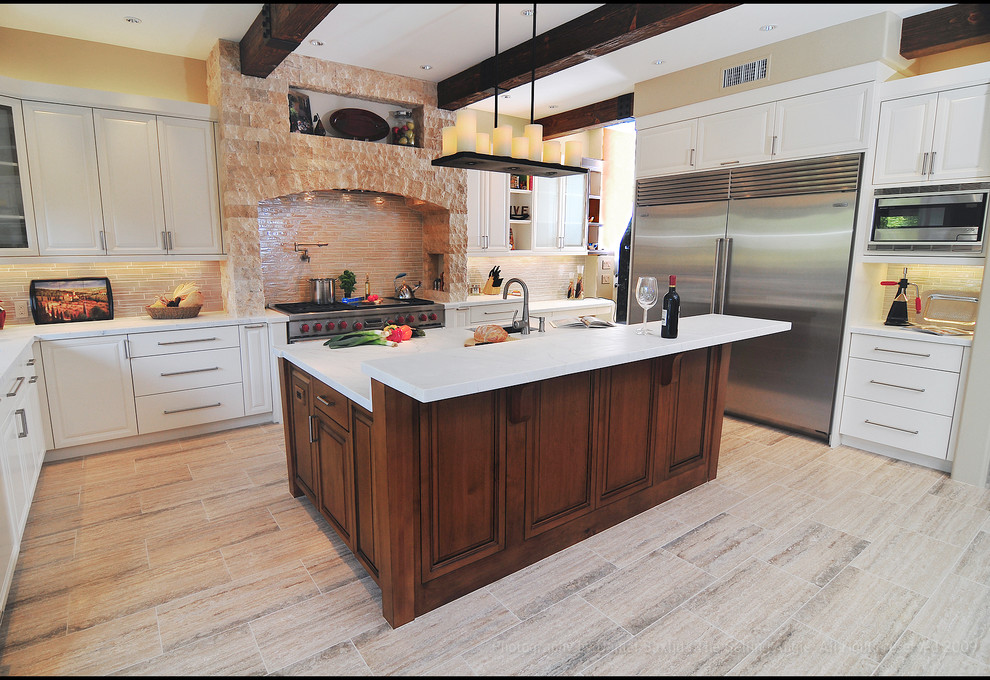Large rustic l-shaped enclosed kitchen in Los Angeles with stainless steel appliances, a double-bowl sink, raised-panel cabinets, white cabinets, marble worktops, beige splashback, stone tiled splashback, an island and light hardwood flooring.